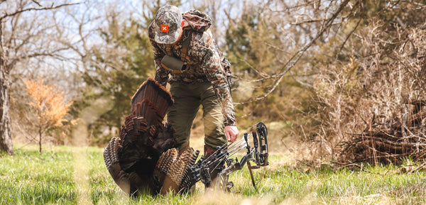 Man holding a Bear Archery bow and a turkey. Find the best bow for turkey hunting.