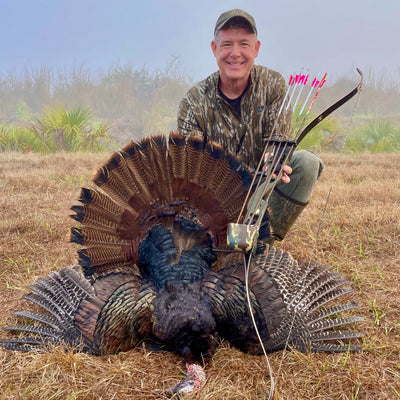 Fred Eichler holds his Fred Eichler Riser  with recurve bow limbs next to a turkey after turkey hunting. Fred Eichler traditional bows for bowhunting can be found at Bear Archery.