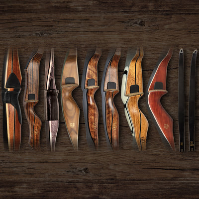 Limited edition Bear Archery traditional bows, both recurve bows and longbows, lined up on a wooden background.