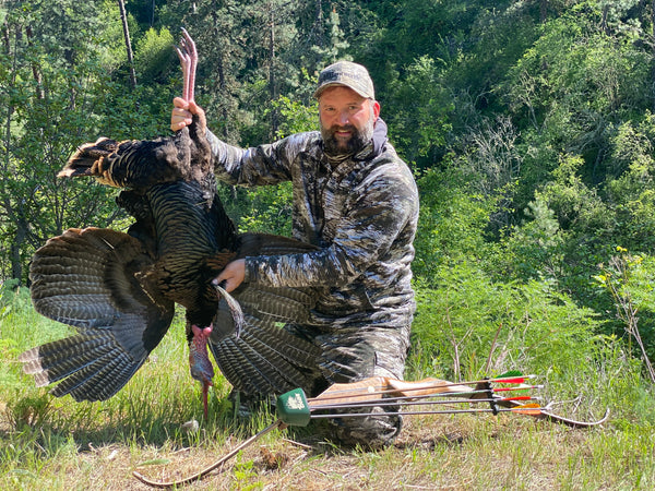 Shane Mowery with Bone Maniacs holding turkey he harvested with Bear Archery Recurve Bow